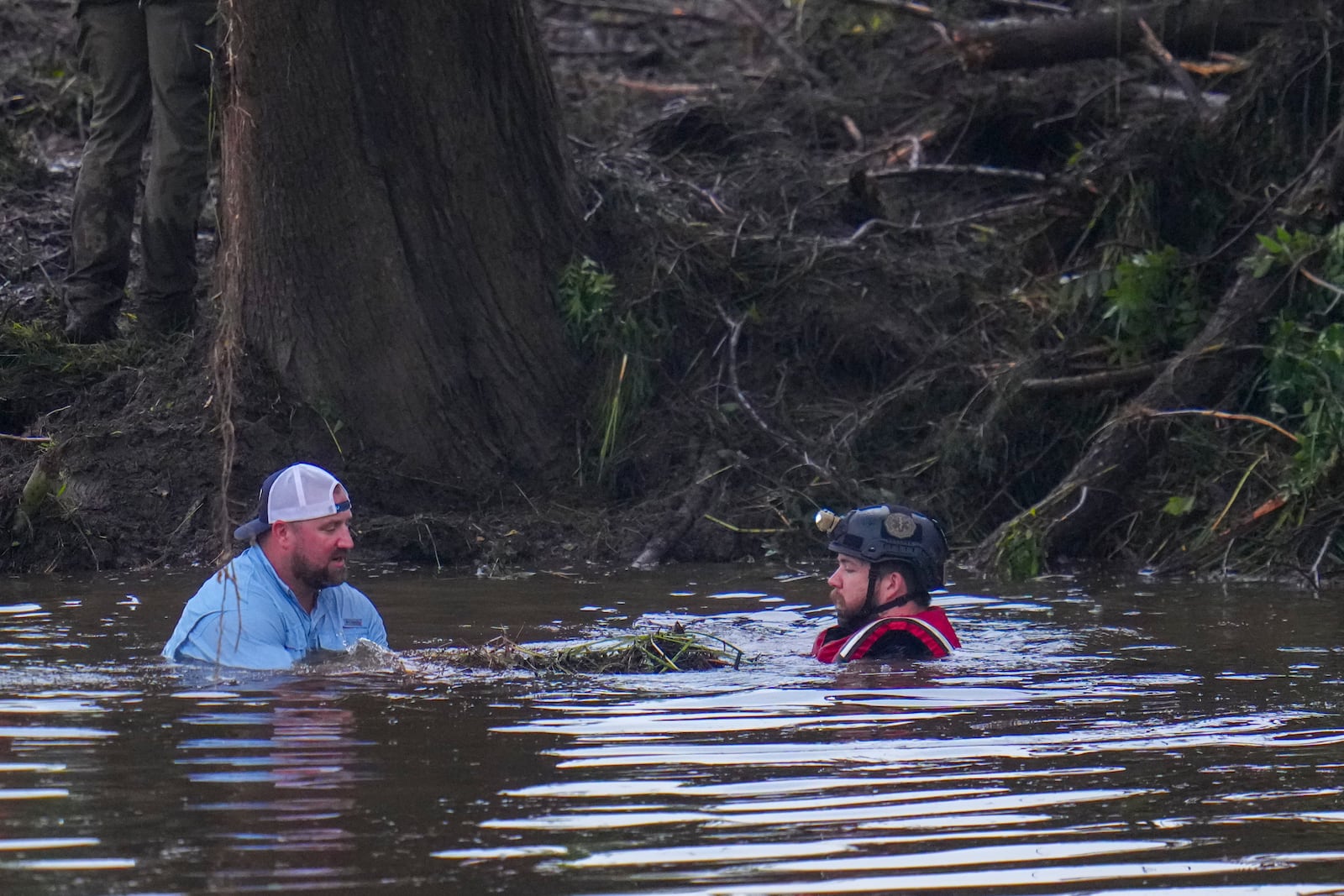 Officials are seen in the Guadalupe River as they assist in recovery efforts after a flash flood swept through the area Sunday, July 6, 2025, in Hunt, Texas. (AP Photo/Julio Cortez)