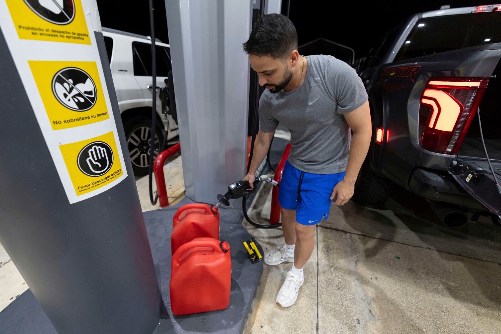 A local fills fuel containers at a gas station in San Juan, Puerto Rico, during an island-wide blackout, Wednesday, April 16, 2025. (AP Photo/Alejandro Granadillo)