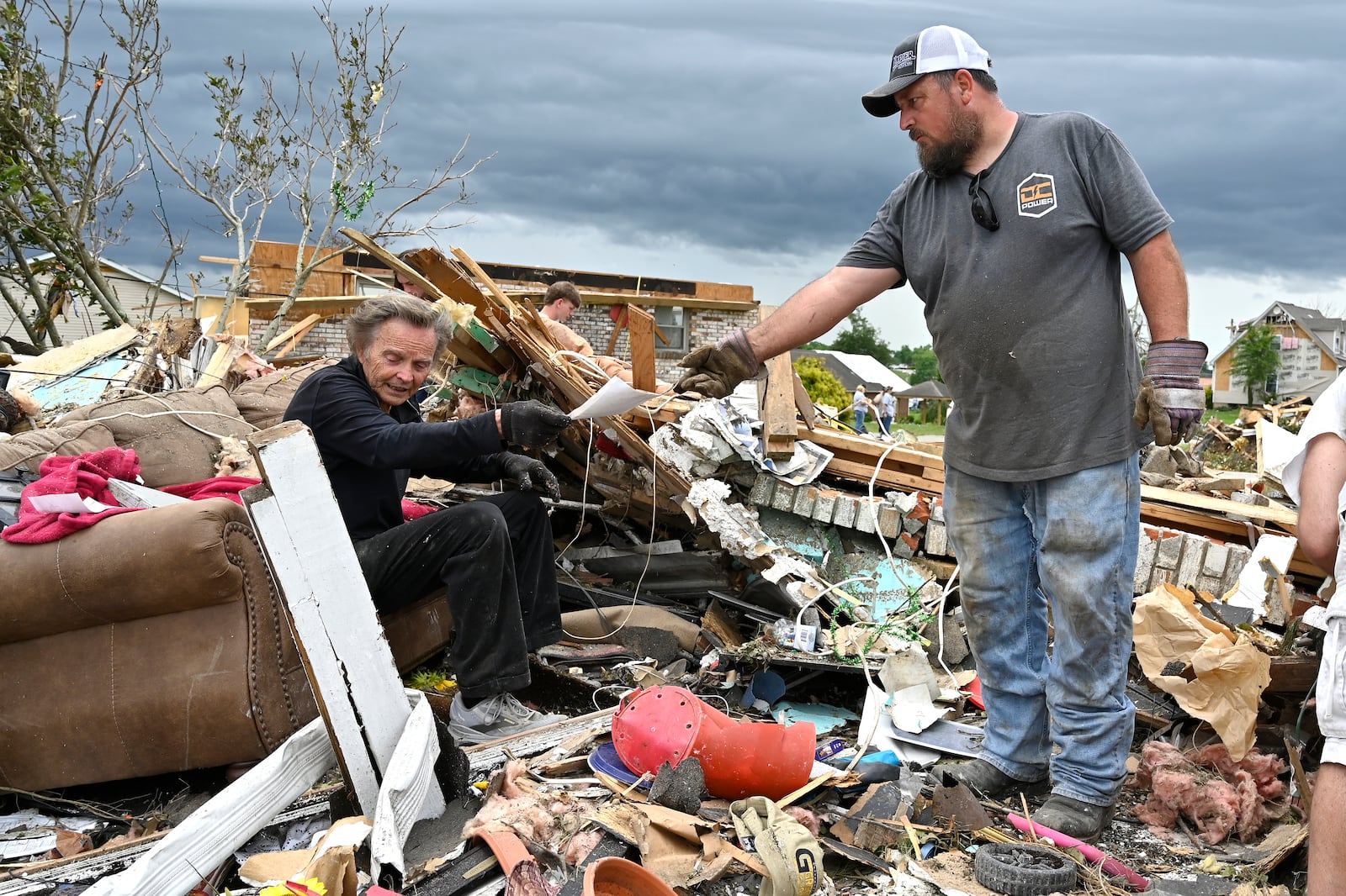 Donovan Queen, right, hands Dam Barnett some photographs that he dug out of the remains of his home in the Sunshine Hills neighborhood in London, Ky., Monday, May 19, 2025. (AP Photo/Timothy D. Easley)