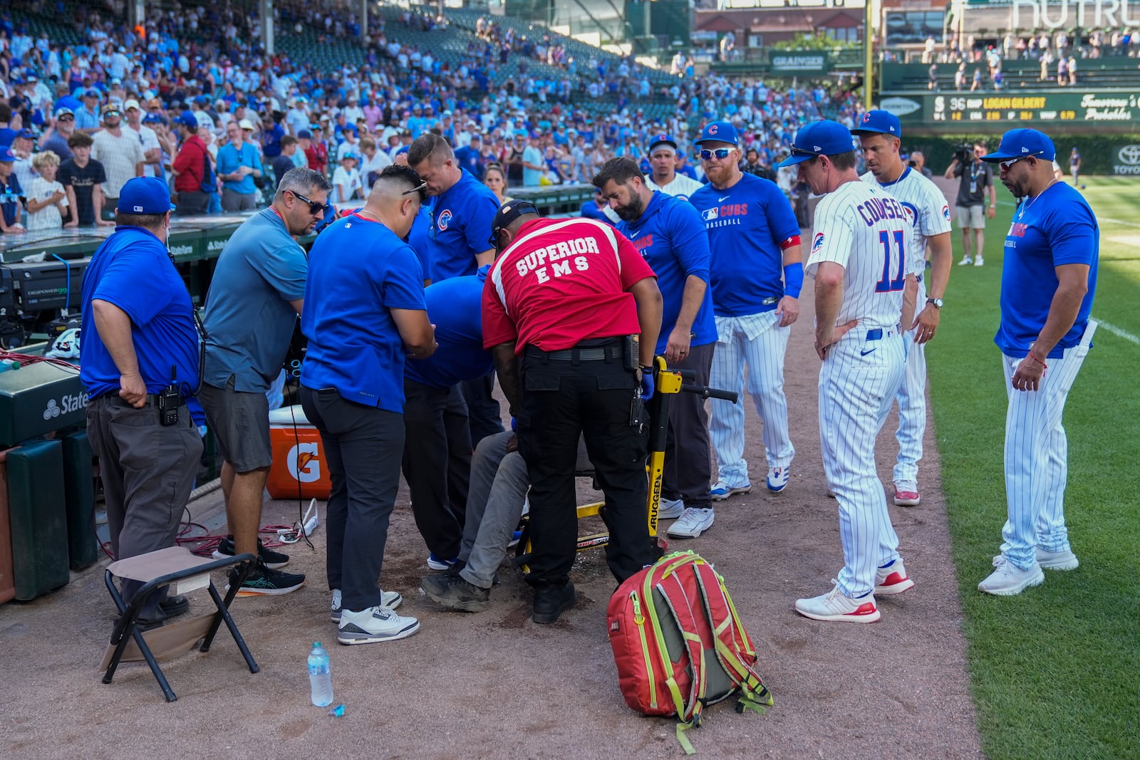 Members of the Chicago Cubs and others stand around as emergency services personnel tend to a Wrigley Field staff member after a hot and humid baseball game against the Seattle Mariners, Saturday, June 21, 2025, in Chicago. (AP Photo/Erin Hooley)