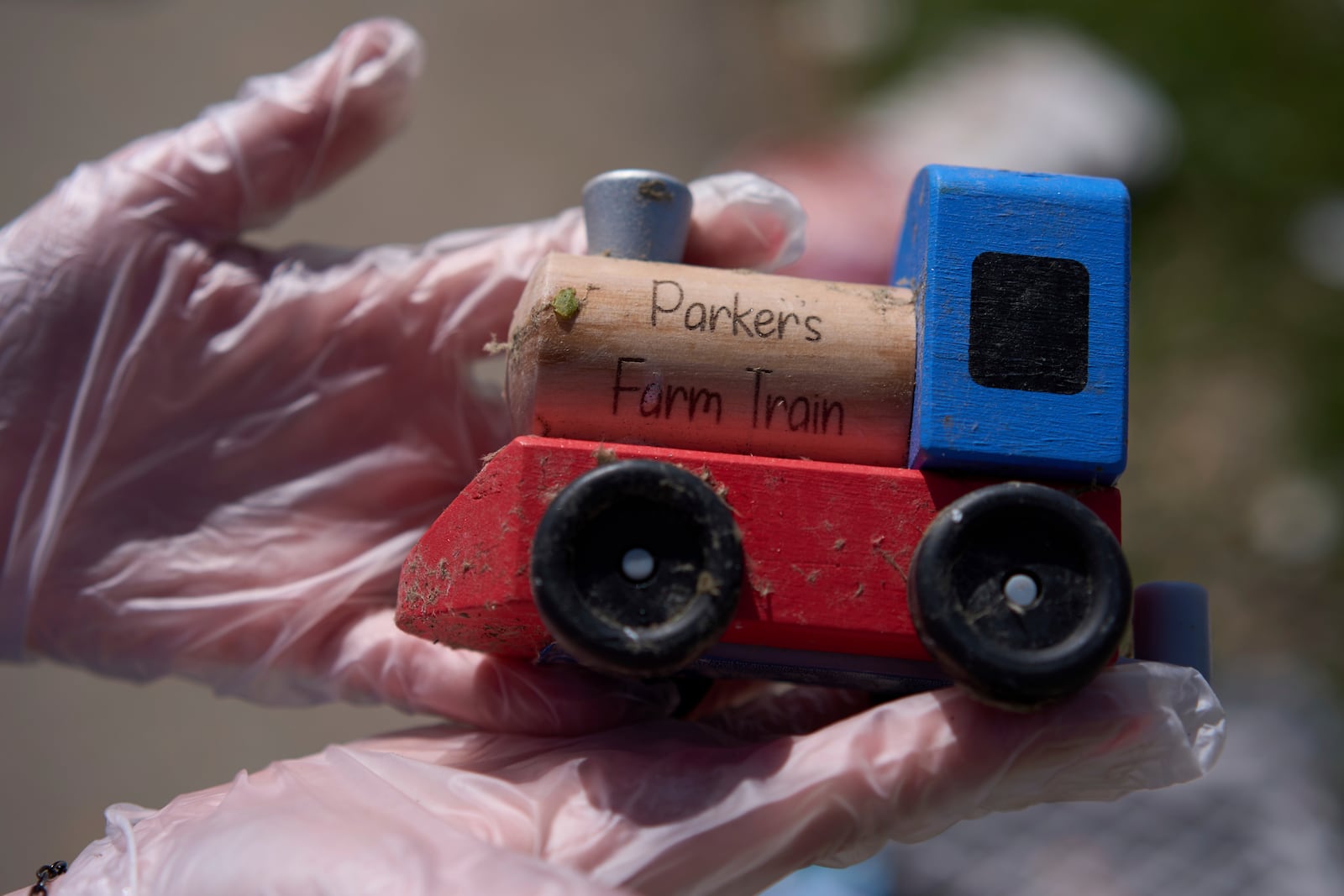 A resident holds her grandson's tory train as she looks for salvageable items of her daughter's destroyed home, Sunday, May 18, 2025, in London, Ky., after a severe storm passed through the area. (AP Photo/Carolyn Kaster)