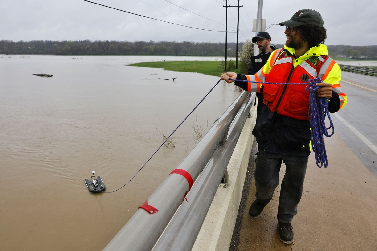 Jeremy Bailey, near, and Alex Hackney, hydrotechs with Miami Conservancy District, collect data at the Great Miami River after several days of heavy rain Saturday, April 5, 2025 on the Ohio 122 bridge in Middletown.  NICK GRAHAM/STAFF