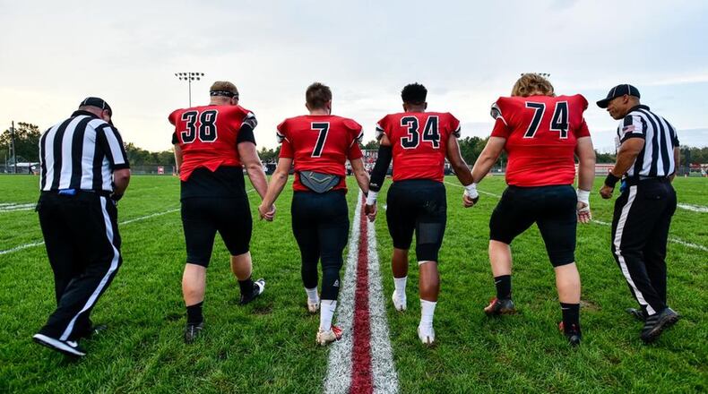 Madison seniors Max Evans (38), Mason Whiteman (7), Evan Crim (34) and Caleb Bolen (74) head out for the coin flip before their 54-0 win over visiting Carlisle on Oct. 5 at Brandenburg Field in Madison Township. NICK GRAHAM/STAFF