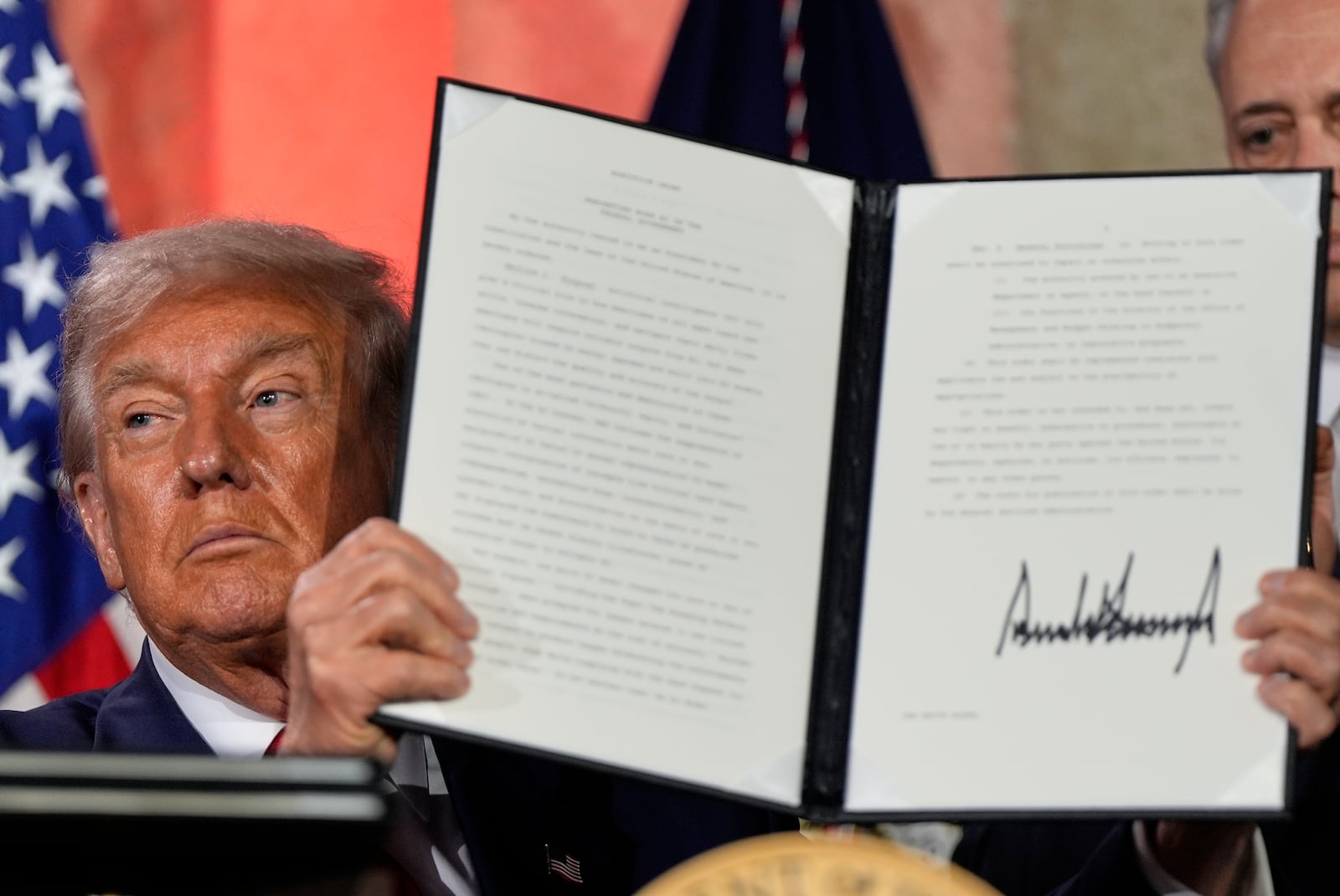President Donald Trump holds a signed executive order after speaking during an AI summit at the Andrew W. Mellon Auditorium, Wednesday, July 23, 2025, in Washington. (AP Photo/Julia Demaree Nikhinson)