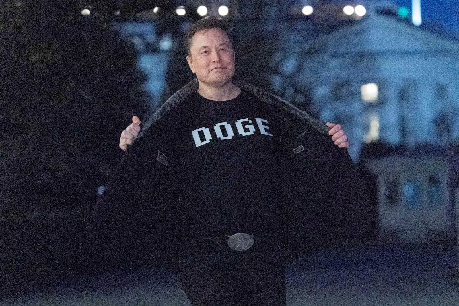 FILE - Elon Musk flashes his t-shirt that reads "DOGE" to the media as he walks on South Lawn of the White House, in Washington, March 9, 2025. (AP Photo/Jose Luis Magana, File)