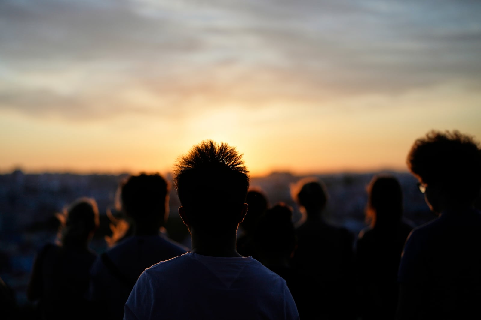 People watch the sun set from the Our Lady of the Hill viewpoint overlooking Lisbon, on a windy Friday, June 27, 2025. (AP Photo/Armando Franca)