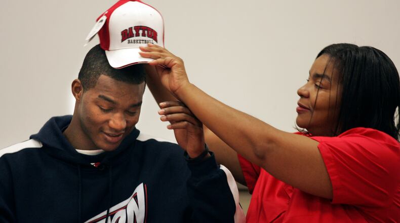 After signing a national letter of intent to play at the University of Dayton, Trotwood Madison basketball star Chris Wright gets at UD hat placed
on his head by his mother Ernestine Grigsby. Photo by Jim Witmer