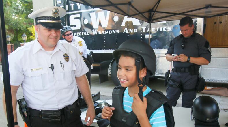 Hamilton Police Officer Scott Arbino helps David Trinidad, 8, try on a SWAT uniform during an Open  House at the Hamilton Police Department headquarters, Thursday, Aug. 10, 2017. GREG LYNCH /  STAFF