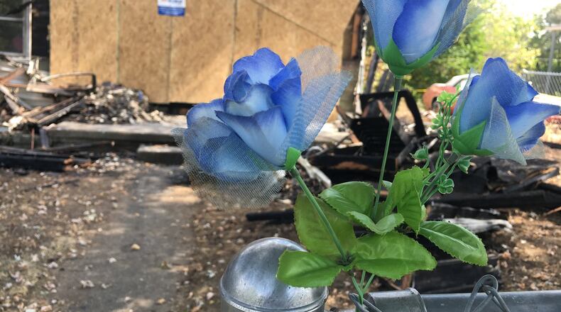 Three artificial blue flowers were attached to a chain-link fence outside a home on Parrish Avenue that caught fire Saturday afternoon. MICHAEL D. PITMAN/STAFF