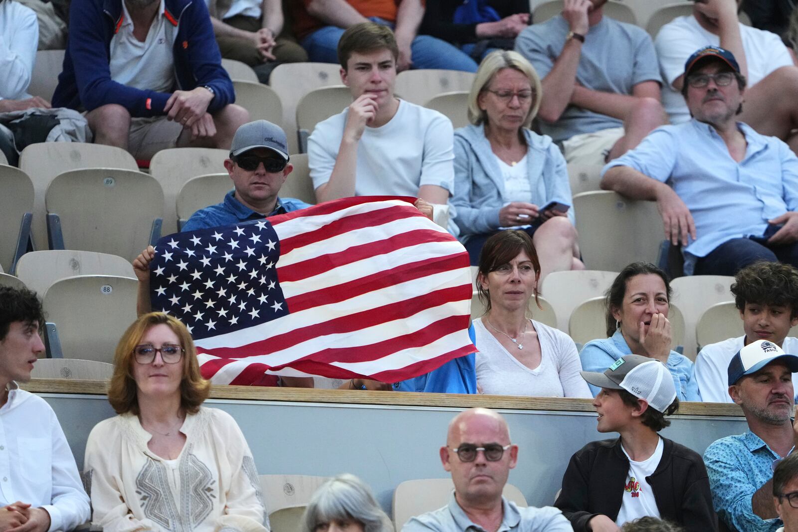 A spectator holds a flag of the United States as he watches the fourth round match of the French Tennis Open between Germany's Daniel Altmaier and Frances Tiafoe of the United States, at the Roland-Garros stadium, in Paris, Sunday, June 1 2025. (AP Photo/Lindsey Wasson)