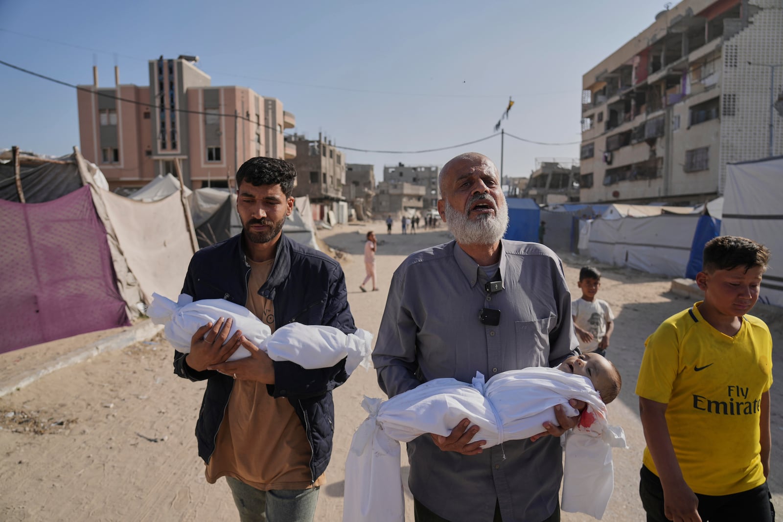 Abdel Rahman Sinwar, left, carries the body of his infant son, Yahia Sinwar, while the child's grandfather carries the body of his one-year-old grandson, Seif Sinwar, both killed in an Israeli army strike in Khan Younis, Gaza Strip, on Saturday, May 3, 2025. (AP Photo/Abdel Kareem Hana)