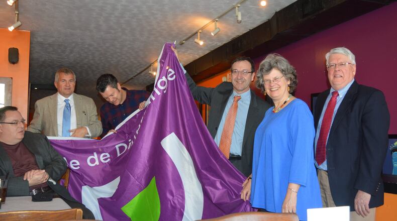 A presentation of a flag of Differdange to the city of Oxford. Pictured, from left, are: Oxford Council member Kevin McKeehan (seated); Tom Ulveling, a member of the Differdange City Council; Henri Kreck , secretary of Differdange, the equivalent of a city manager here; Thierry Leterre, the dean of the Miami University Dolibois European Center in Luxembourg; Oxford Mayor Kate Rousmaniere and City Manager Doug Elliott. CONTRIBUTED/BOB RATTERMAN