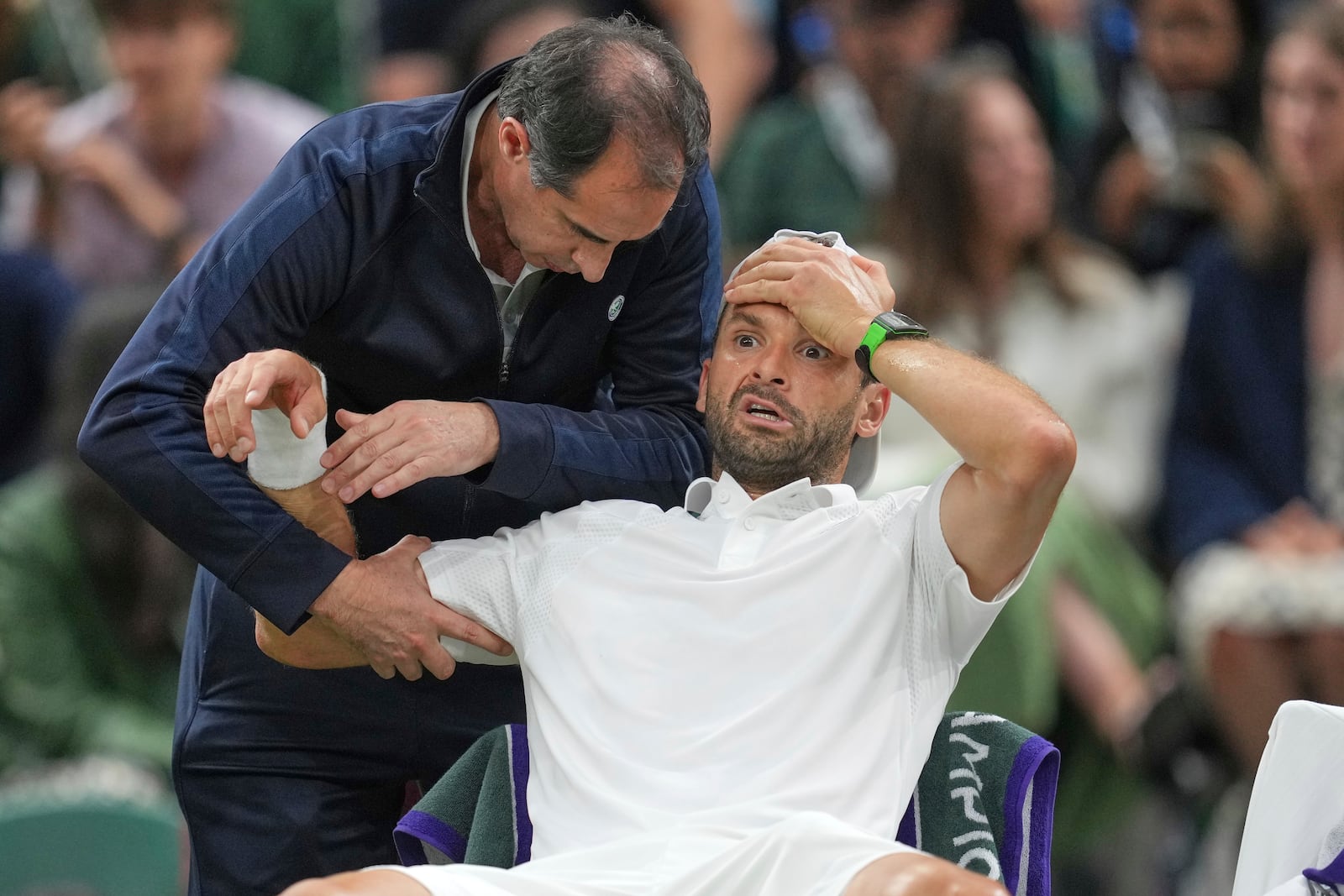Bulgaria's Grigor Dimitrov gets treatment after he went down with an injury which forced him to retire injured from a fourth round men's singles match against Italy's Jannik Sinner at the Wimbledon Tennis Championships in London, Monday, July 7, 2025. (AP Photo/Kin Cheung)