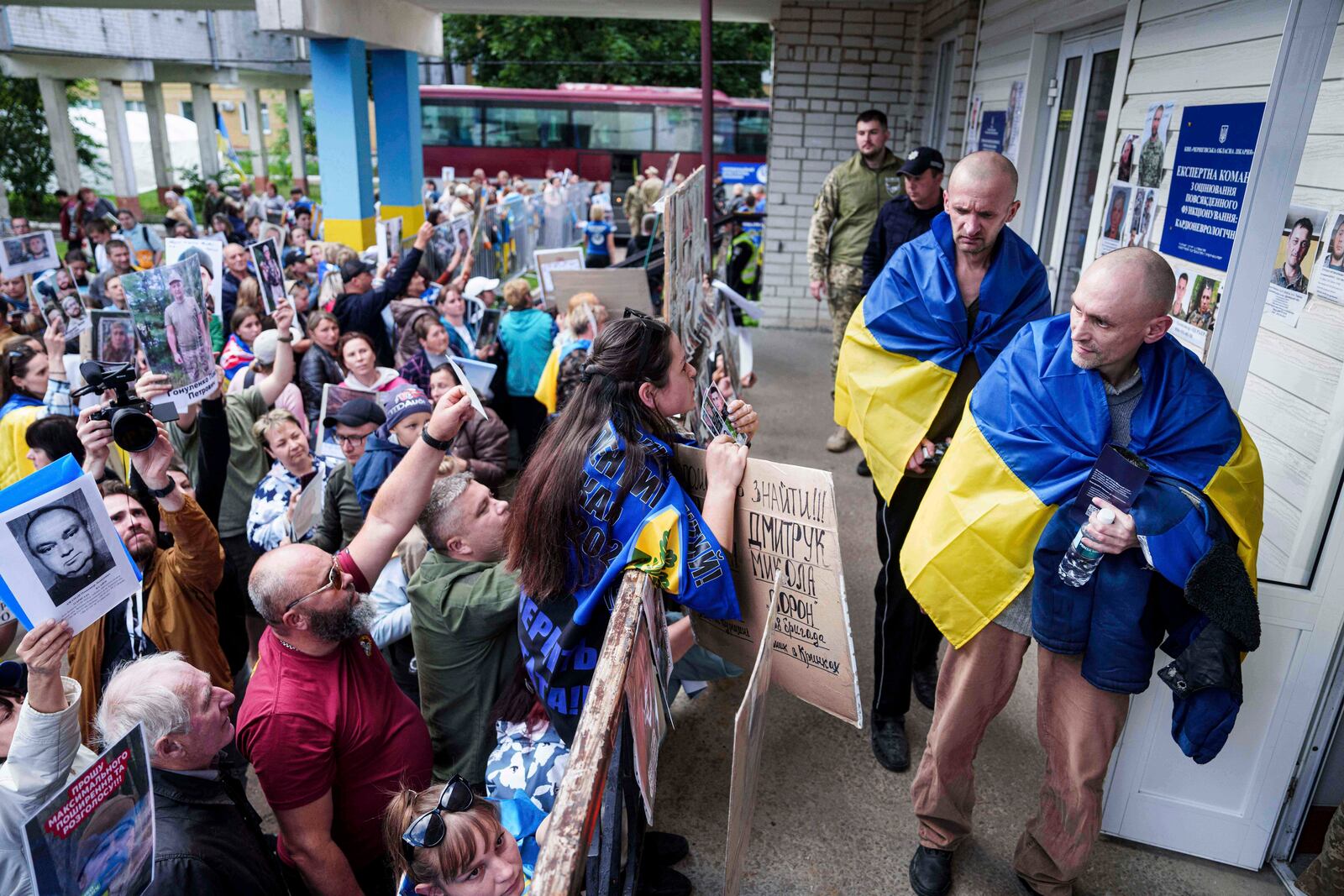 Ukrainian soldiers walk in front of a crowd of people holding photos of their missed relatives after returning from captivity after a POWs exchange between Russia and Ukraine, in Chernyhiv region, Ukraine, Thursday, June 26, 2025. (AP Photo/Evgeniy Maloletka)