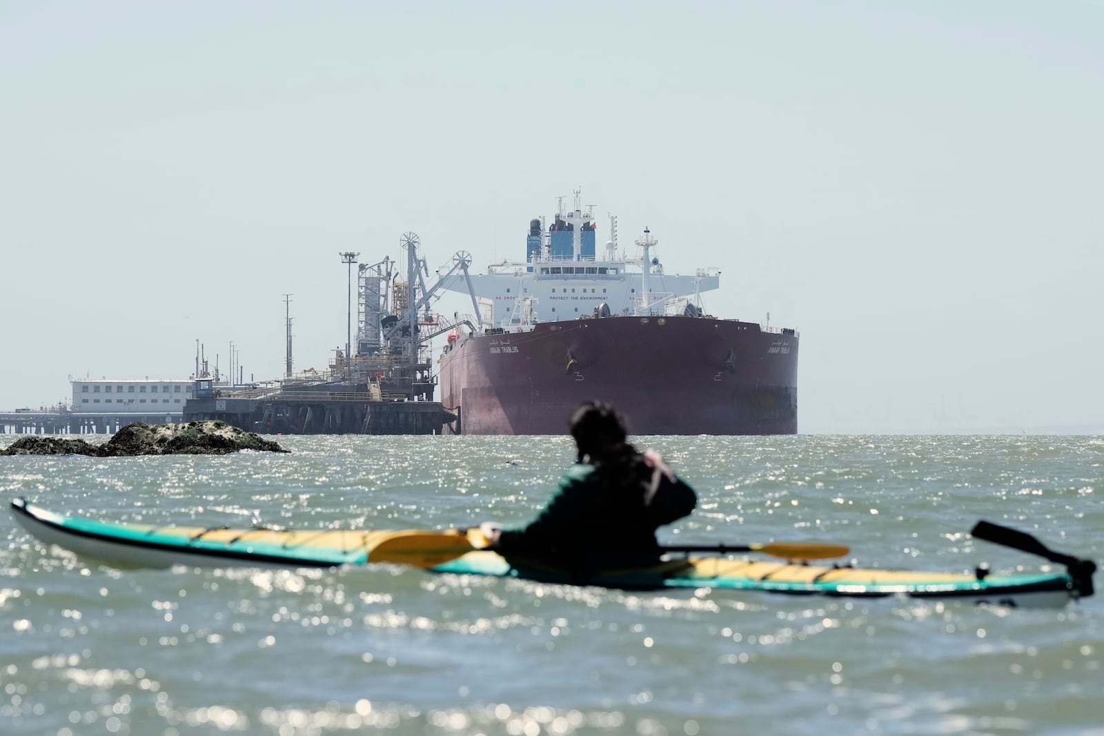 Juan Bay, president of the Waorani people of Ecuador, foreground, looks at an oil tanker docked at the Chevron Long Wharf, Thursday, June 19, 2025, in Richmond, Calif. (AP Photo/Godofredo A. Vásquez)