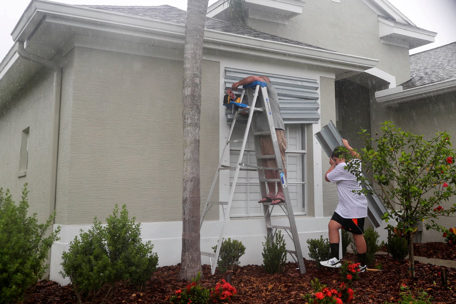 FILE - Tim Mullen, and Michael Brissette, cover their windows with hurricane shutters in preparation for Tropical Storm Elsa, Tuesday, July 6, 2021 in Tampa, Fla. (Arielle Bader/Tampa Bay Times via AP,File)