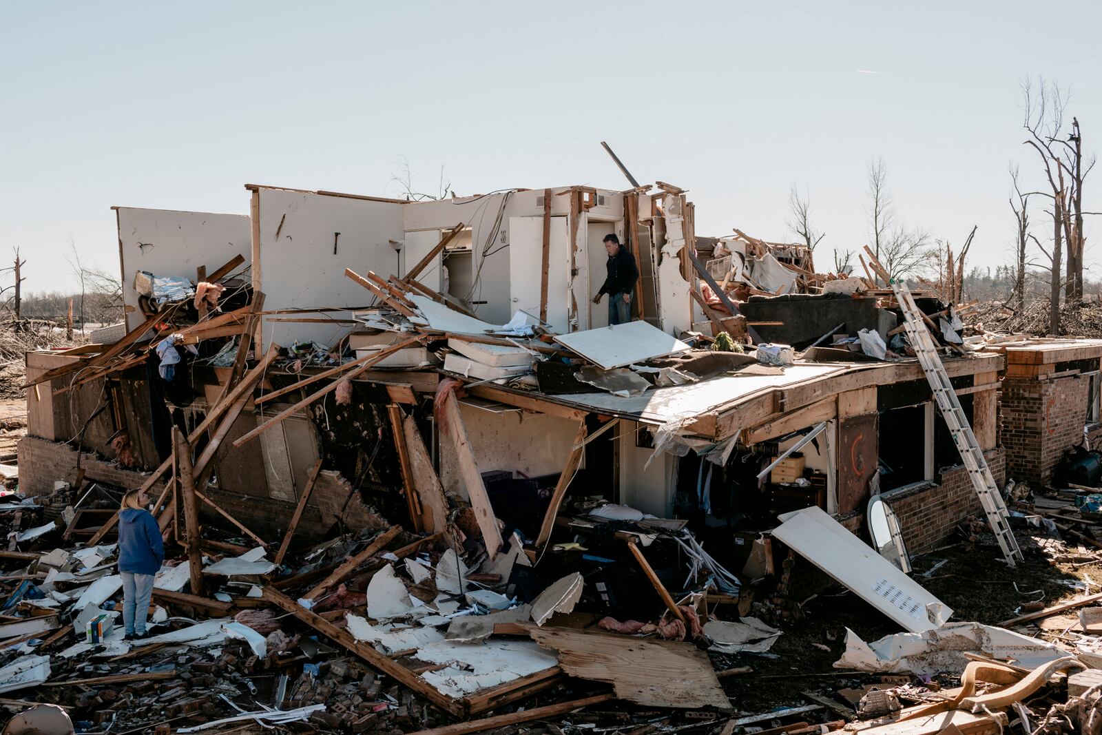 Hal Latham, center, salvages documents from the second floor apartment of his girlfriend Dawn Humphrey, lower left, at the Dawson Village Apartments complex in Dawson Springs, Ky., on Monday, Dec. 13, 2021, where a tornado flattened much of the town on Friday night. Determining how many people died in the tornadoes that ravaged the central U.S. on Friday has been a challenging task so far, with estimates fluctuating as search teams continue to spread out amid vast fields of rubble in an effort to rescue the living and account for the dead. (William Widmer/The New York Times)