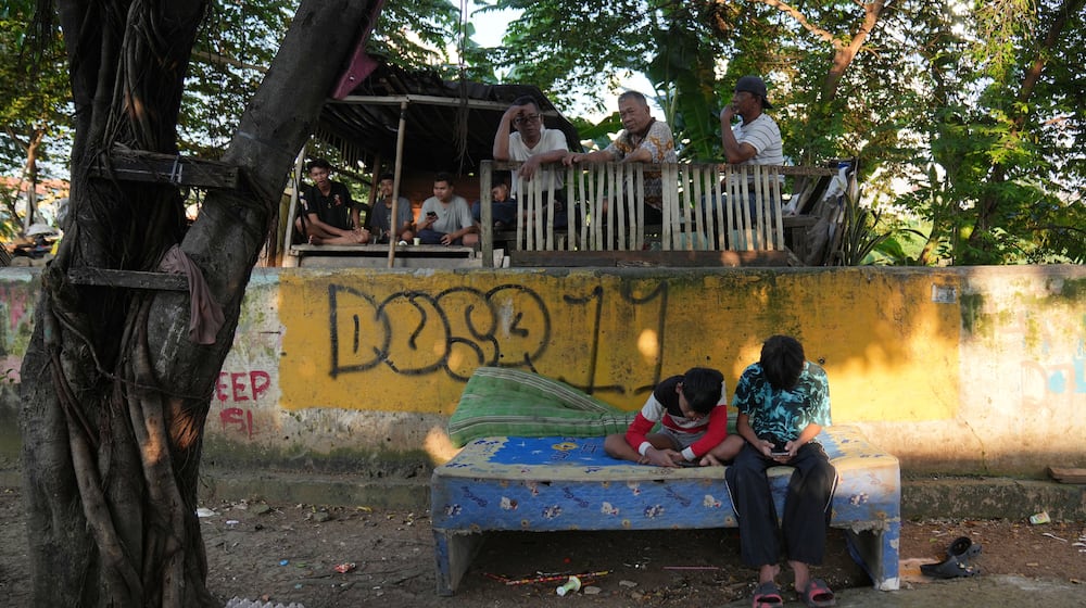 Teenage boys use their mobile phone in Jakarta, Indonesia, March 16, 2026. (AP Photo/Dita Alangkara)
