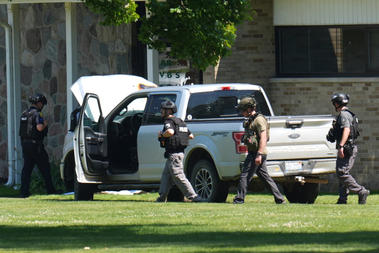 Police walk by an idle vehicle near CrossPointe Community Church in Wayne, Mich., Sunday, June 23, 2025. (AP Photo/Paul Sancya)