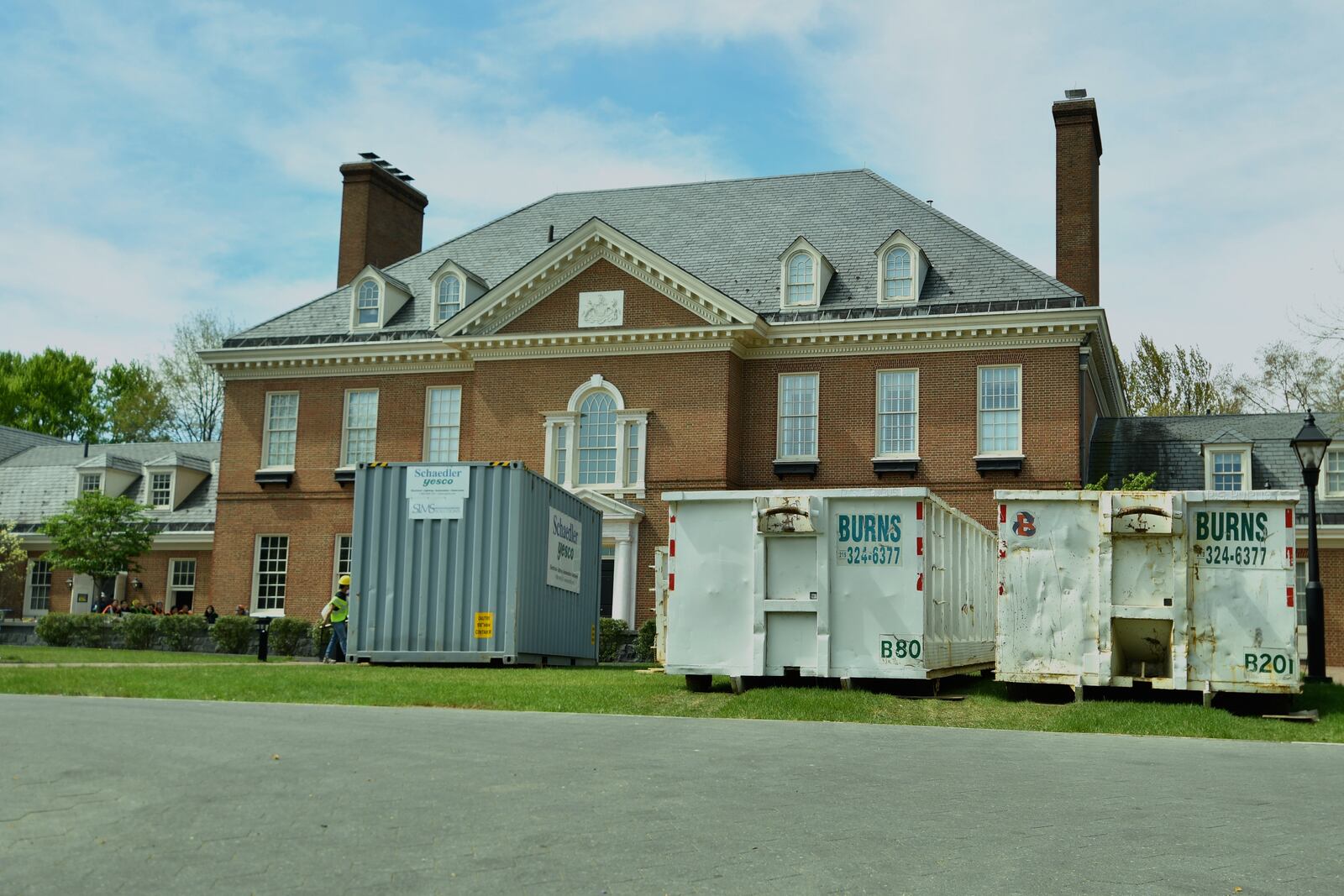 Large waste disposal bins sit out front of the Pennsylvania governor's residence as crews work to tear out fire-damaged ceilings, walls and floors nine days after an alleged arsonist's fire engulfed part of the residence's south wing, Tuesday, Apr. 22, 2025, in Harrisburg, Pa. (AP Photo/Marc Levy)