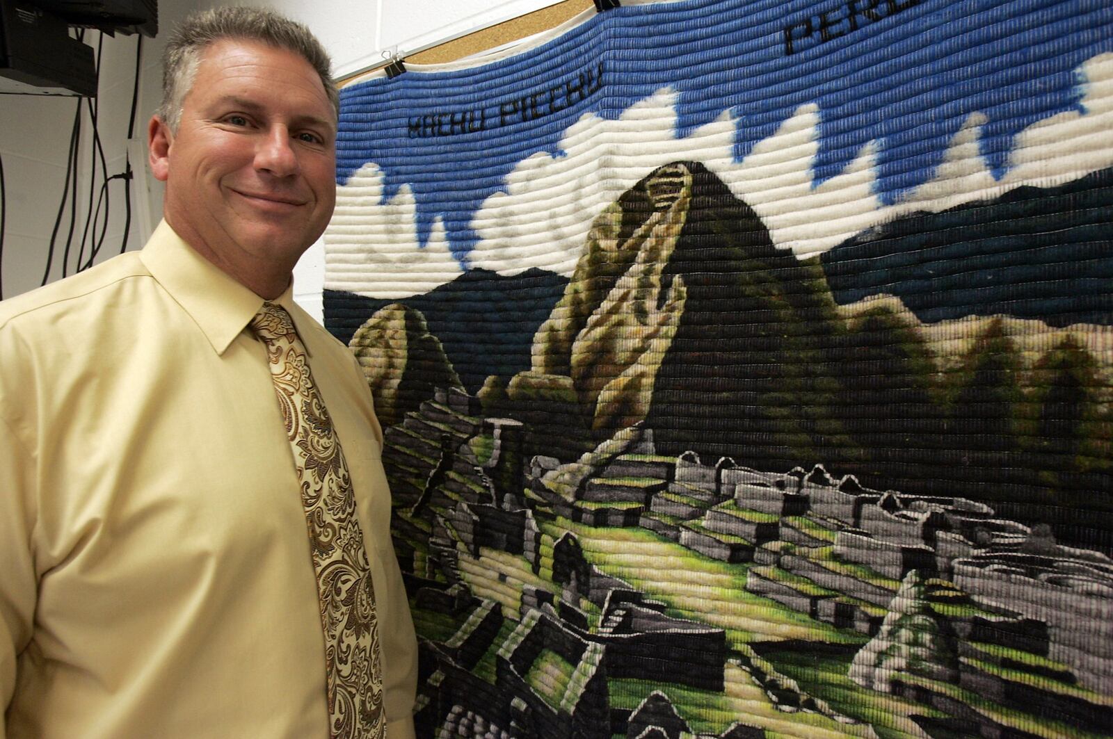 Bob Evick poses with an Alpaca wool poster of an Inca village in Peru in his Madison High School social studies classroom on Sept. 9, 2010. Evick, along with his wife and daughter, visited the actual village the previous summer. JOURNAL-NEWS FILE PHOTO