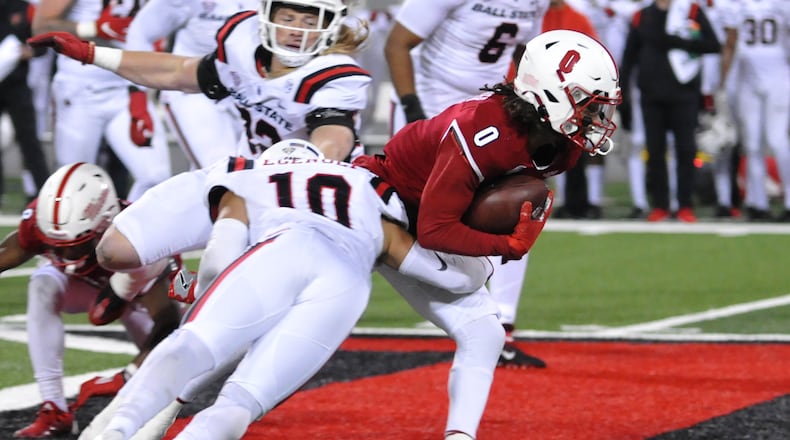 Miami's Mac Hippenhammer, 0, attempts to run out of the tackle of Ball State's Ben Egenolf, 10, during the first quarter of a Mid American Conference game on Tuesday, Nov. 22. DAVID A. MOODIE/CONTRIBUTING PHOTOGRAPHER