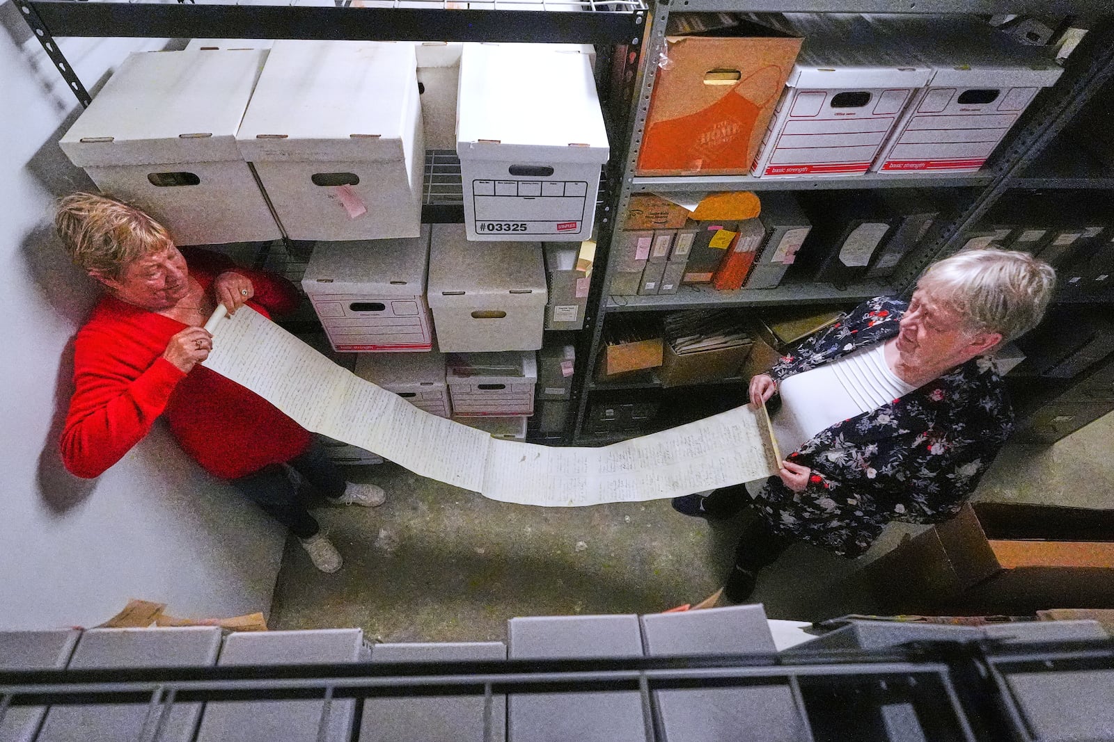 Historian Jennifer Cromack, left, and Rev. Diane Badger unfurl a recently found, 178-year-old anti-slavery scroll which was found in a storage box at Grotonwood, the home mission of The American Baptist Churches of Massachusetts, Thursday, June 26, 2025, in Groton, Mass. (AP Photo/Charles Krupa)