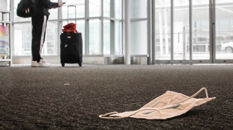 A discarded mask lay on the floor at Dayton International Airport. JIM NOELKER/STAFF