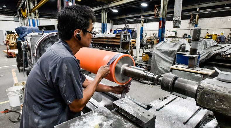 Hoa Dao polishes a roller to specification at Cent-Roll Products Inc. in Fairfield. The company makes is hiring for grinding positions and several temporary laborer positions. NICK GRAHAM/STAFF
