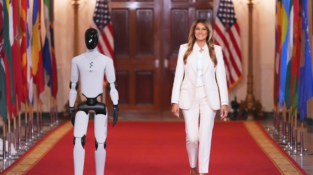First lady Melania Trump arrives, accompanied by a robot, to attend the "Fostering the Future Together Global Coalition Summit," with other first spouses, at the White House, Wednesday, March 25, 2026, in Washington. (AP Photo/Jacquelyn Martin)