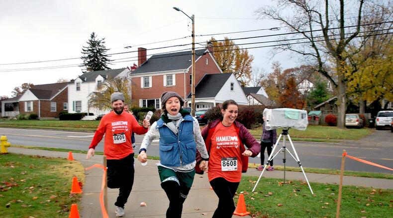 Eric Stephenson, Kristen Santos and Katie Stephenson cross the finish line at the Young Lives 5K fundraiser, which drew a record crowd on Thanksgiving Day in Hamilton.