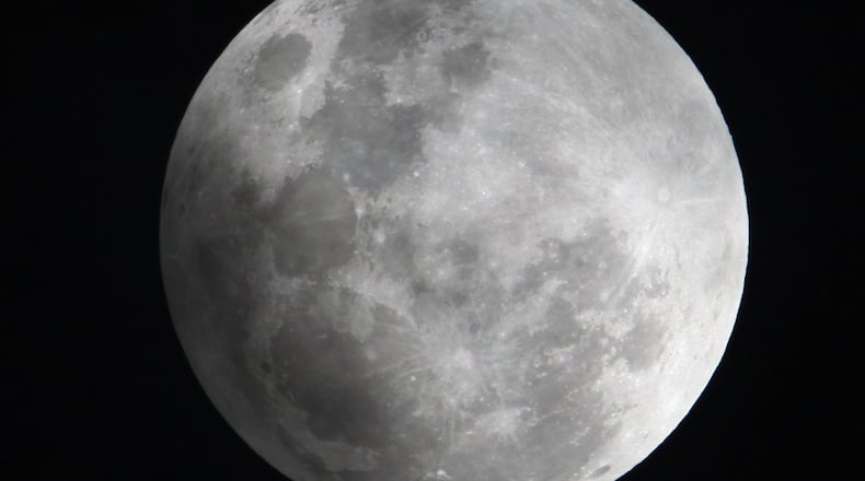In this Monday Feb. 9, 2009 photo, a faint shadow from the Earth is cast over part of the Moon during a penumbral lunar eclipse, seen from Manila, Philippines. Early Saturday, Feb. 11, 2017, a partial eclipse and Comet 45P will share the sky. BULLIT MARQUEZ/ASSOCIATED PRESS