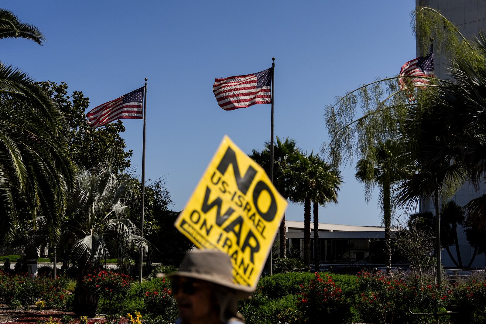 An anti-war demonstrator holds a sign outside the Wilshire Federal Building in Los Angeles Sunday, June 22, 2025, following U.S. airstrikes on Iran's nuclear facilities. (AP Photo/Jae C. Hong)