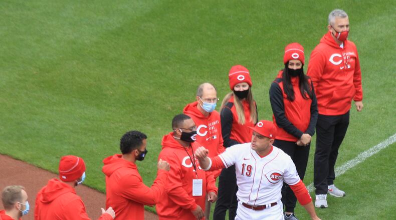 Joey Votto, of the Reds, slaps hands with members of the staff during a pregame ceremony on Opening Day on Thursday, April 1, 2021, at Great American Ball Park in Cincinnati. David Jablonski/Staff