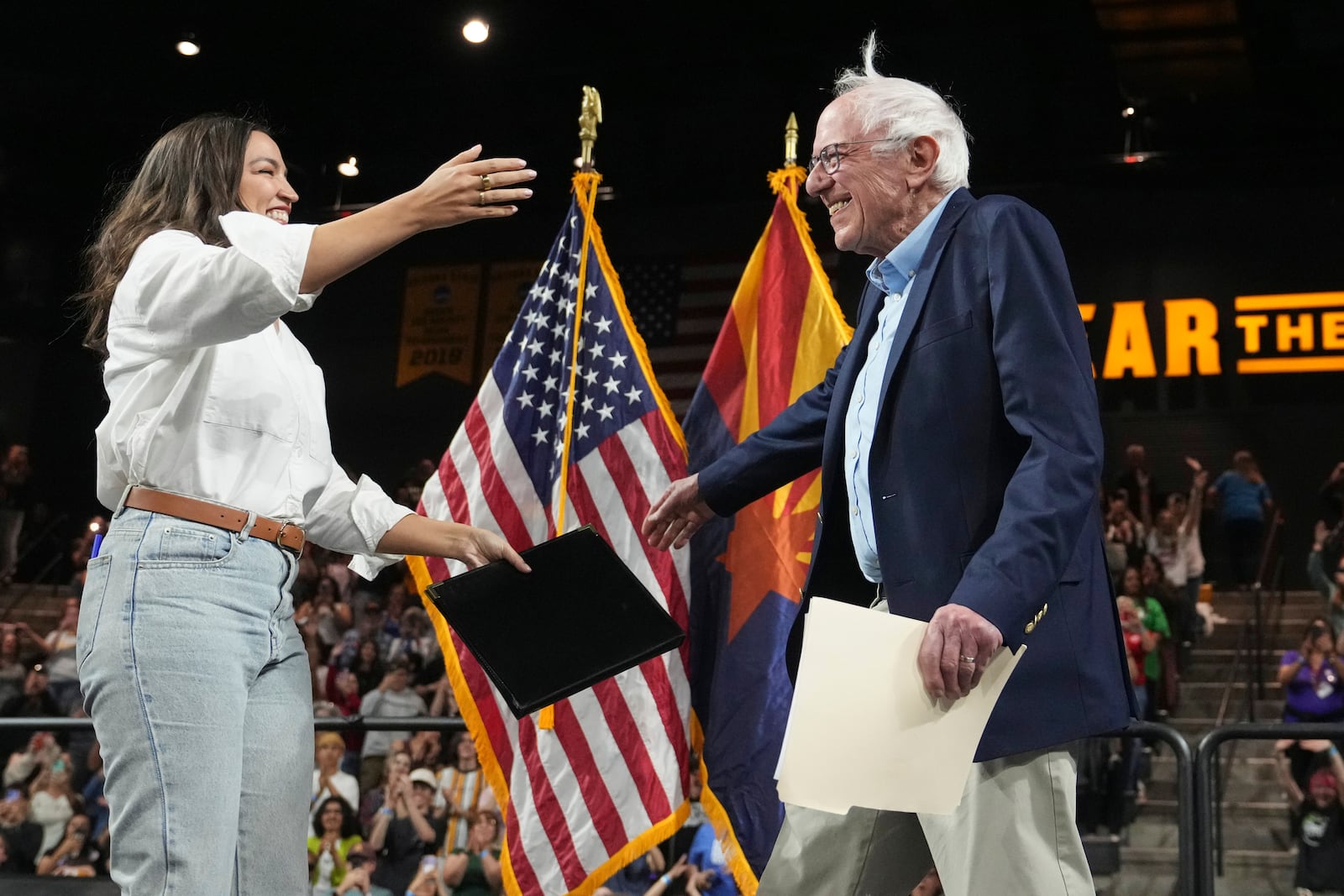 FILE - Rep. Alexandria Ocasio-Cortez, D-N.Y., left, greets Sen. Bernie Sanders, I-Vt., right, as he arrives to speak during a "Fighting Oligarchy" tour event at Arizona State University, March 20, 2025, in Tempe, Ariz. (AP Photo/Ross D. Franklin, File)