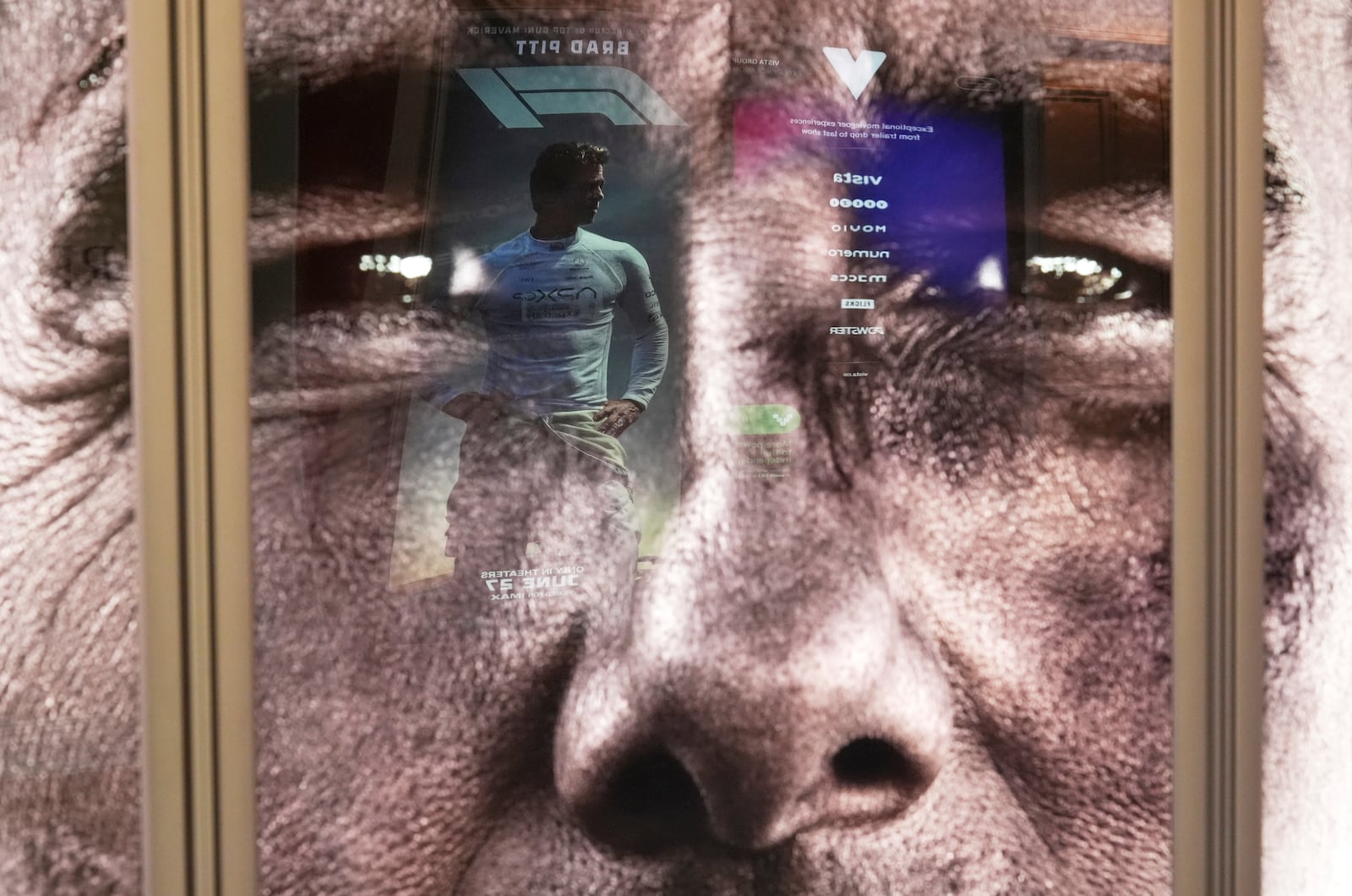 An image of actor Brad Pitt from the upcoming film "F1" is reflected in an advertisement for Tom Cruise's new film "Mission: Impossible - The Final Reckoning" on the opening day of CinemaCon, the official convention of Cinema United, on Monday, March 31, 2025, at Caesars Palace in Las Vegas. (AP Photo/Chris Pizzello)