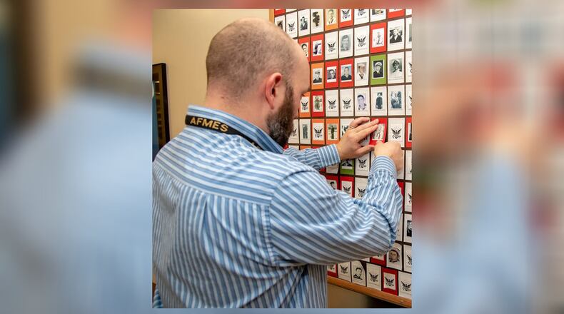 Sean Patterson, Air Forces Medical Examiner Systems Department of Defense Quality Management DNA Analyst, replaces a photo of U.S. Navy Fireman First Class Billy Johnson signifying him as the 200th person identified of those killed on Dec. 7, 141 when the USS Oklahoma was attacked during Pearl Harbor. More than 400 sailors and Marines were killed on the Oklahoma. SUBMITTED PHOTO