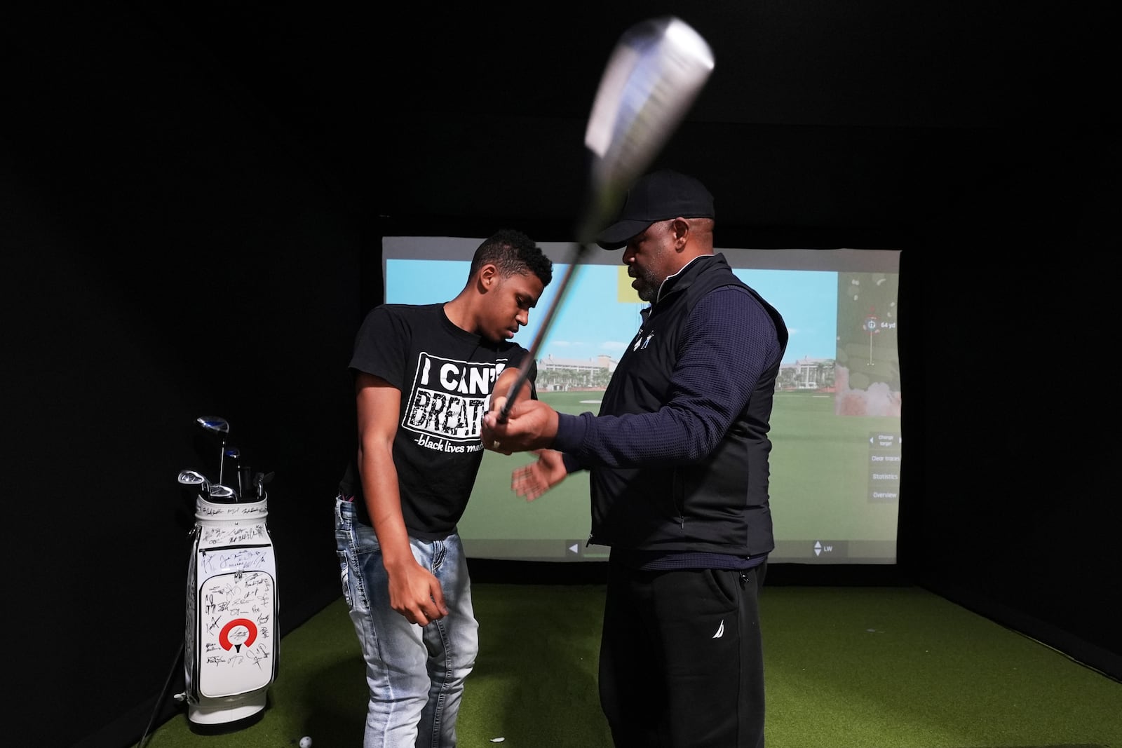 Jacento White, 16, a junior at Renaissance High School works on his swing with golf coach Jess Hawkins in Detroit, Thursday, Feb. 27, 2025. (AP Photo/Paul Sancya)