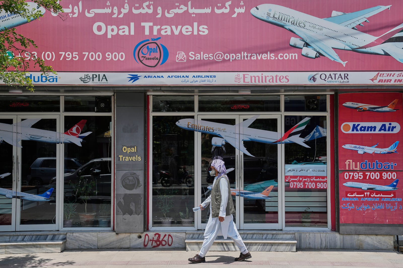 An Afghan person passes in front of an air travel agency in Kabul, Afghanistan, Thursday, June 5, 2025. (AP Photo/Ebrahim Noroozi)