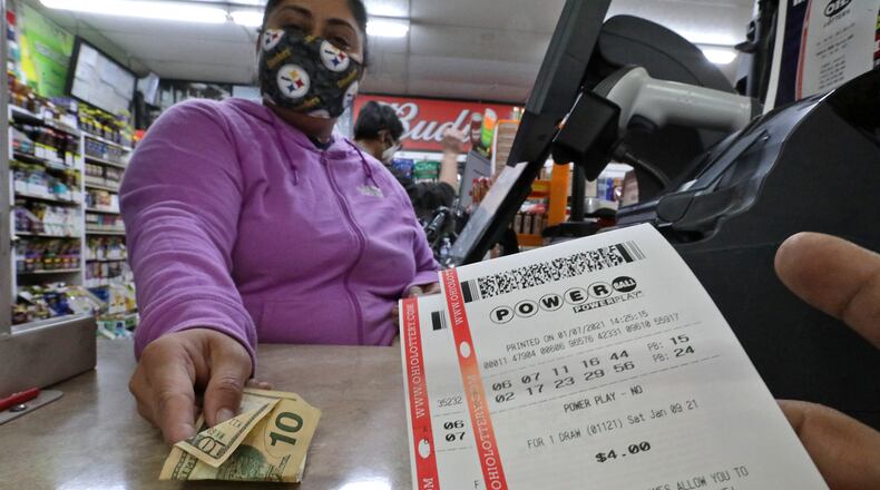 A customer purchases Mega Million and Powerball tickets from Hiral Patel Thursday at the Plum Food Mart in Springfield. BILL LACKEY/STAFF