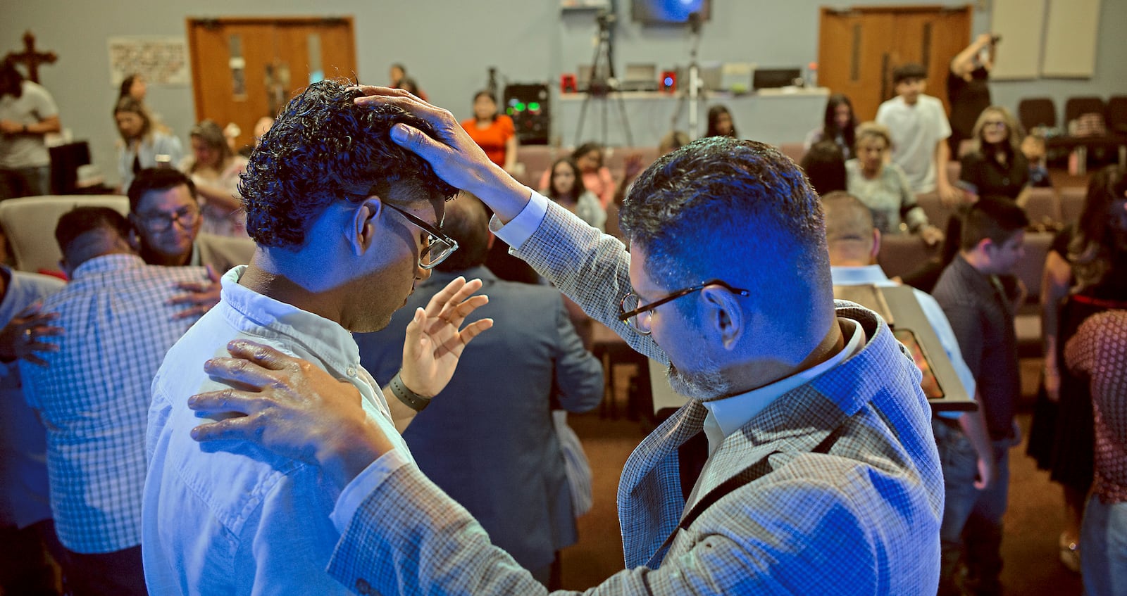José Luis Orozco, a pastor from Nicaragua, places his hand on his son, Josias, 17, as he prays for him and the congregation of the Oasis Church, in Taylor, Texas, June 15, 2025. (AP Photo/Rodolfo Gonzalez)