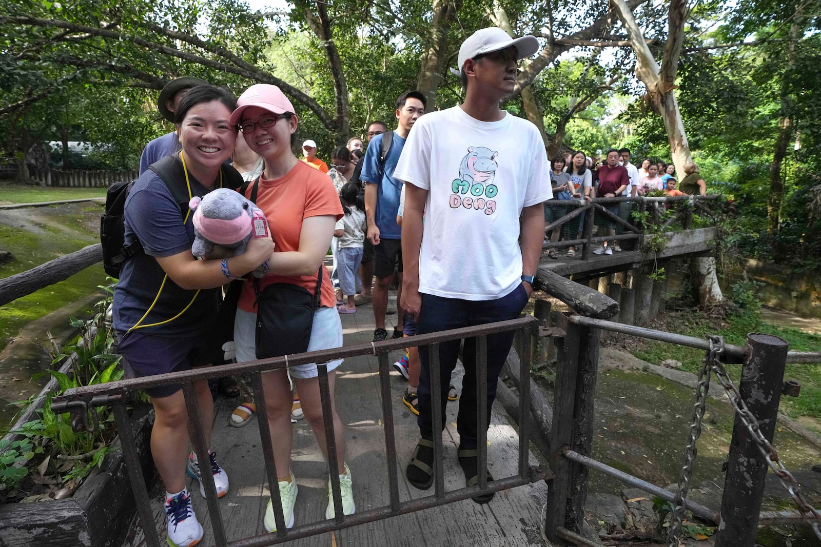 Visitors hold a soft toy of hippo Moo Deng as they lin up to watch Moo Deng, which turned one year old, at the Khao Kheow Open Zoo in Chonburi province, Thailand, Thursday, July 10, 2025. (AP Photo/Sakchai Lalit)