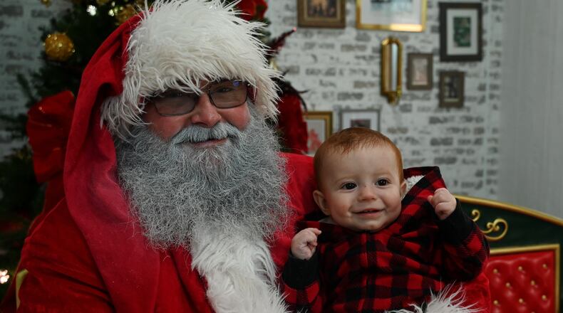 Michael Fields, who's been Santa at the Santa House in Hamilton for the past 10 years, holds Archer Kuhn, 8 months, of Ross Twp., during a visit Friday afternoon, Dec. 20, 2024. MICHAEL D. PITMAN/STAFF