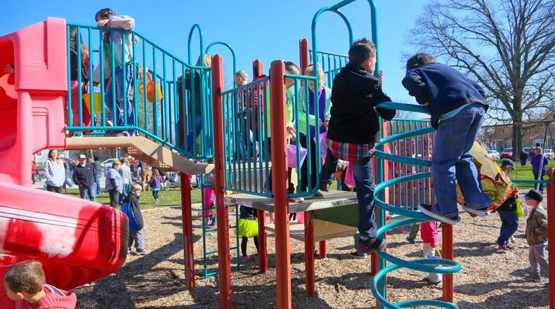 Children search the playset for hidden Easter eggs during the Easter egg hunt at the Lindenwald splash pad at Benninghofen playground in Hamilton. FILE