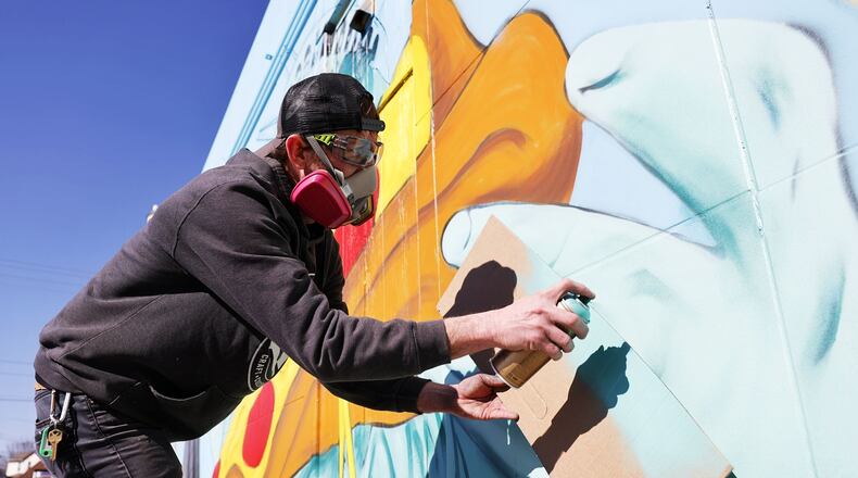 Brian Beck works on a wall mural outside Calabria Pizza Monday, March 24, 2025 on Main Street in Hamilton. NICK GRAHAM/STAFF