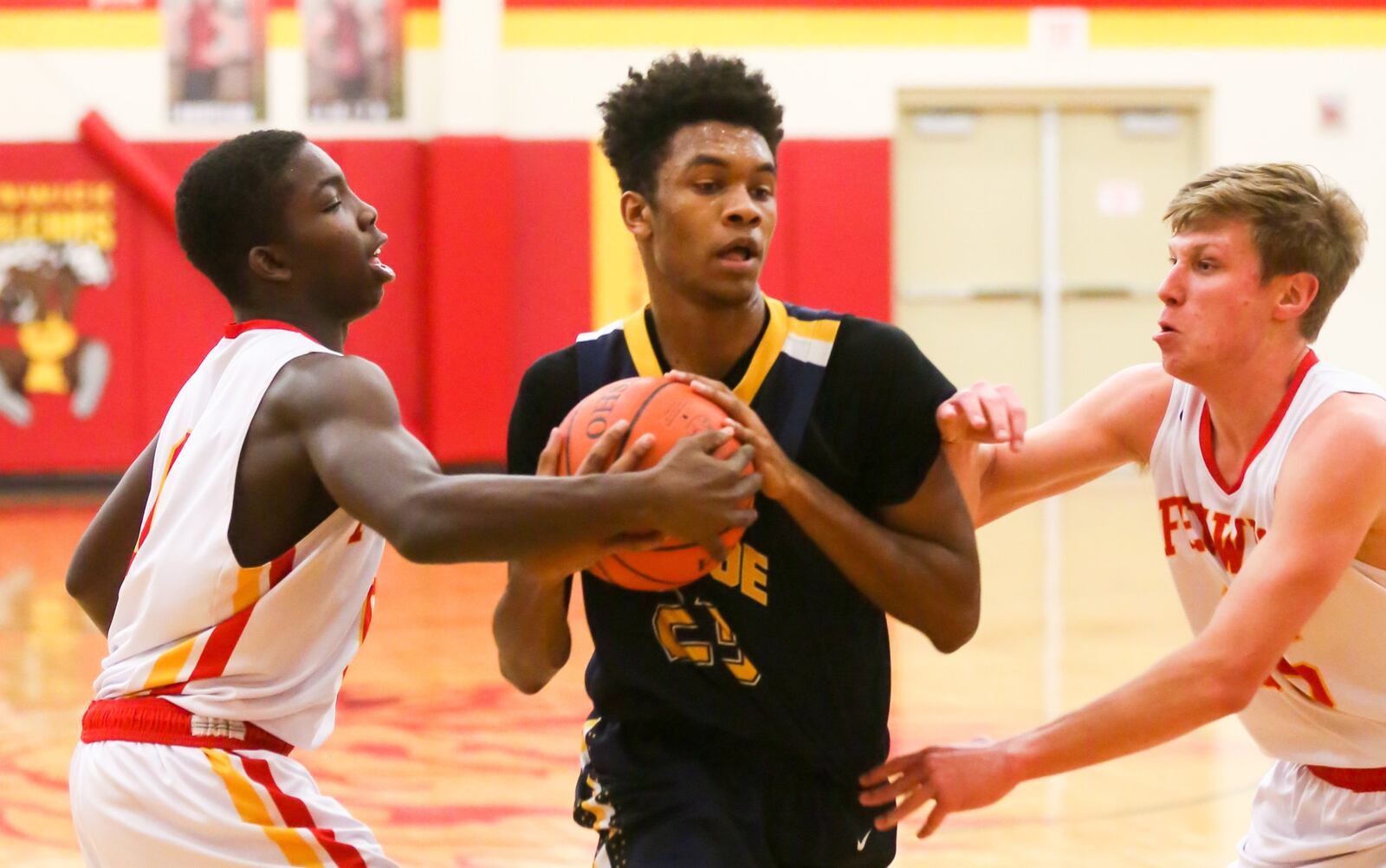 Monroe forward Tristan Backas (23) is tied up by Fenwick’s Caleb Davis (left) and Luke Bradshaw (right) during Tuesday night’s game at Fenwick. GREG LYNCH/STAFF