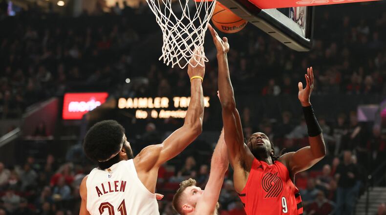 Portland Trail Blazers forward Jerami Grant, right, drives to the basket beside Cleveland Cavaliers forward Dean Wade, center, and center Jarrett Allen, right, during the first half of an NBA basketball game, Sunday, Feb. 1, 2026, in Portland, Ore. (AP Photo/Amanda Loman)