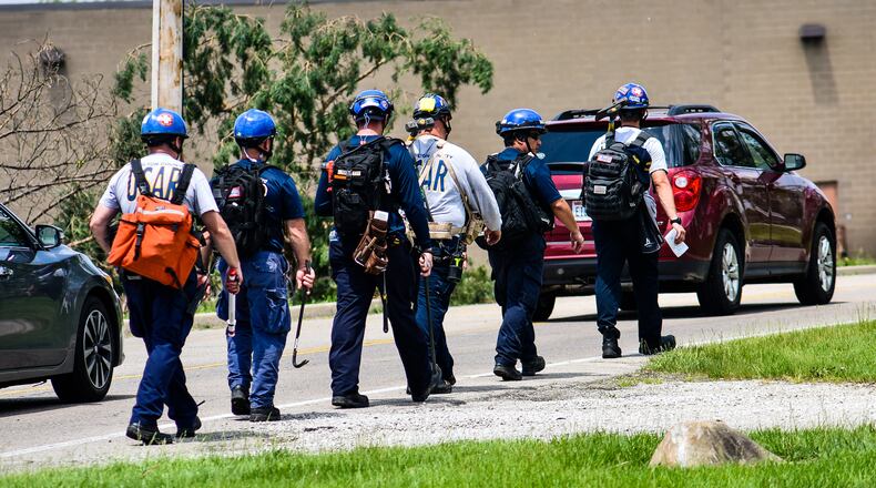 Houses, businesses and vehicles in Trotwood were damage by tornadoes late Monday night, May 27. Many streets were blocked for downed trees, power lines and debris scattered through the neighborhoods. This emergency crew from Hamilton County is walking to help those in need in the area. NICK GRAHAM/STAFF