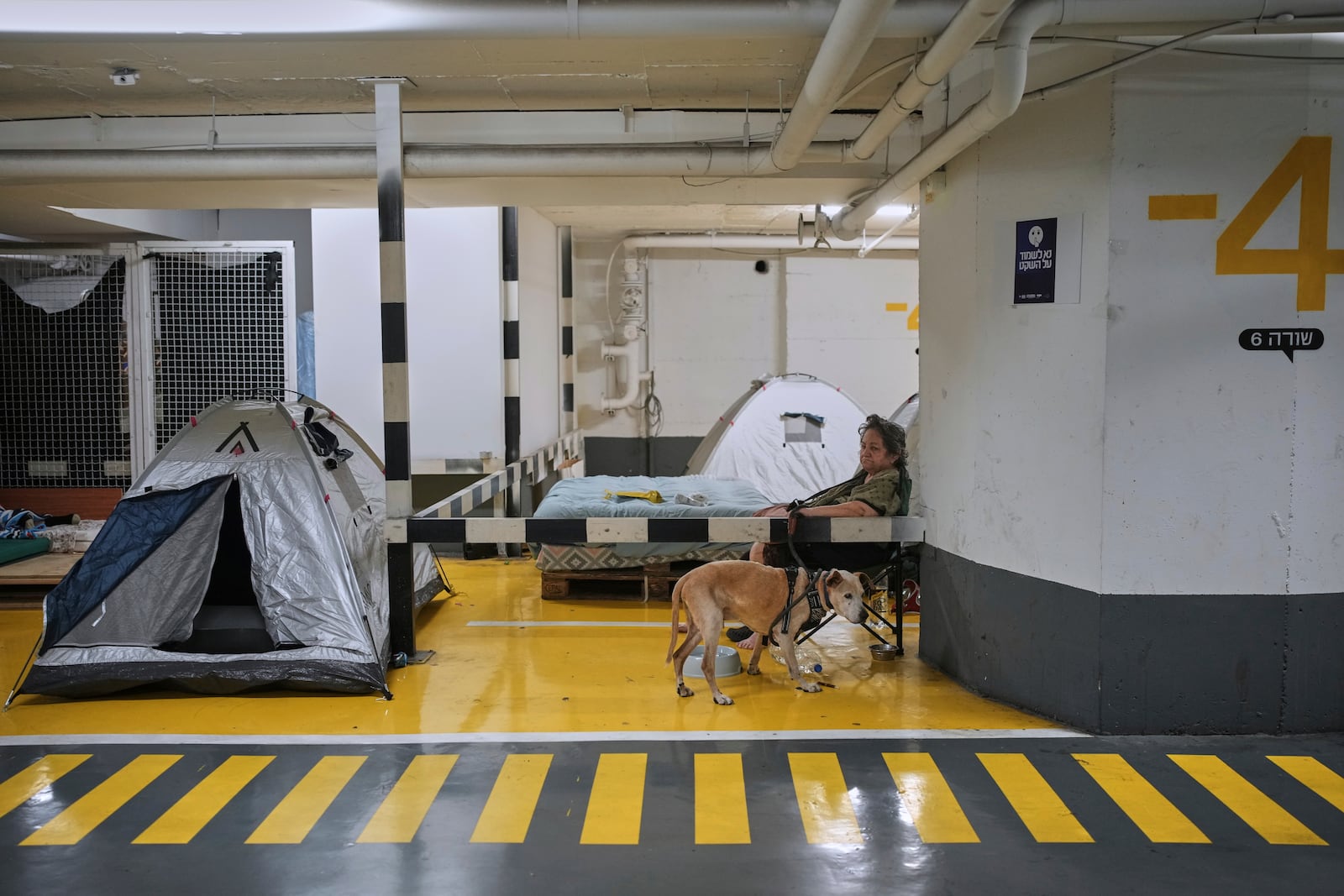 People take shelter in a parking garage as a precaution against possible Iran missile attacks, in Tel Aviv, Israel, Wednesday, June 18, 2025. (AP Photo/Ohad Zwigenberg)