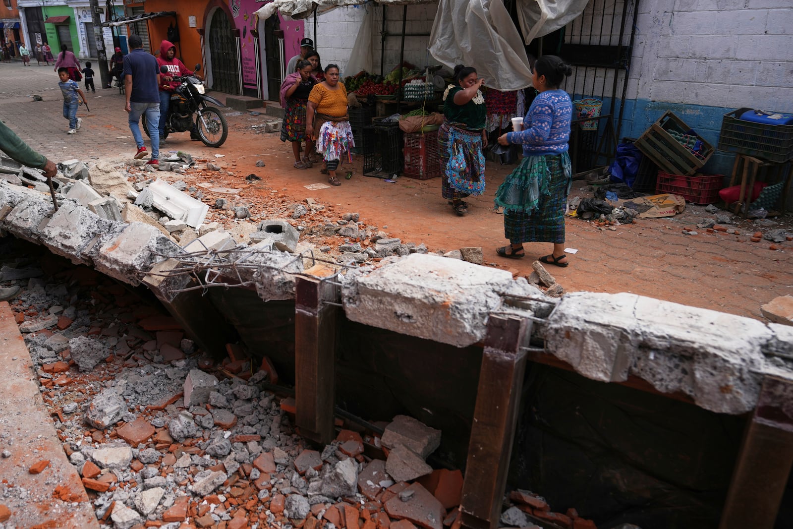 Residents walk past debris from damaged houses in Santa Maria de Jesus, Guatemala, Wednesday, July 9, 2025, following dozens of earthquakes and aftershocks that were recorded in a matter of hours. (AP Photo/Moises Castillo)